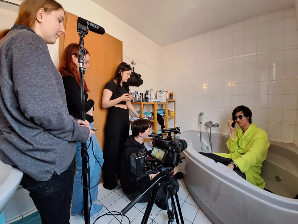  Behind-the-Scenes-Aufnahme eines Drehs im Badezimmer, das Team arbeitet konzentriert an einer Szene.