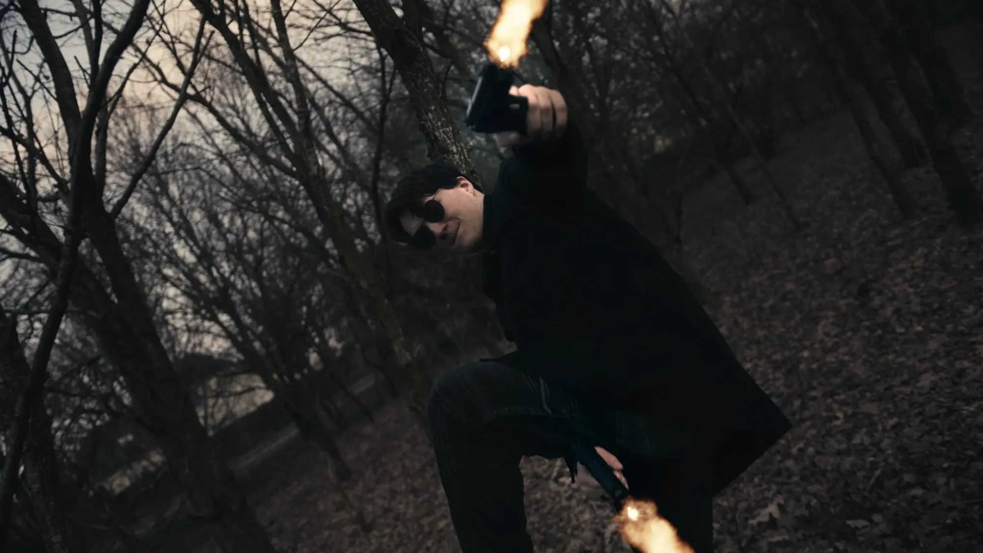 Action-Szene aus Leidenschaft - Eine Person in dunklem Mantel feuert eine Waffe in einem düsteren Wald.