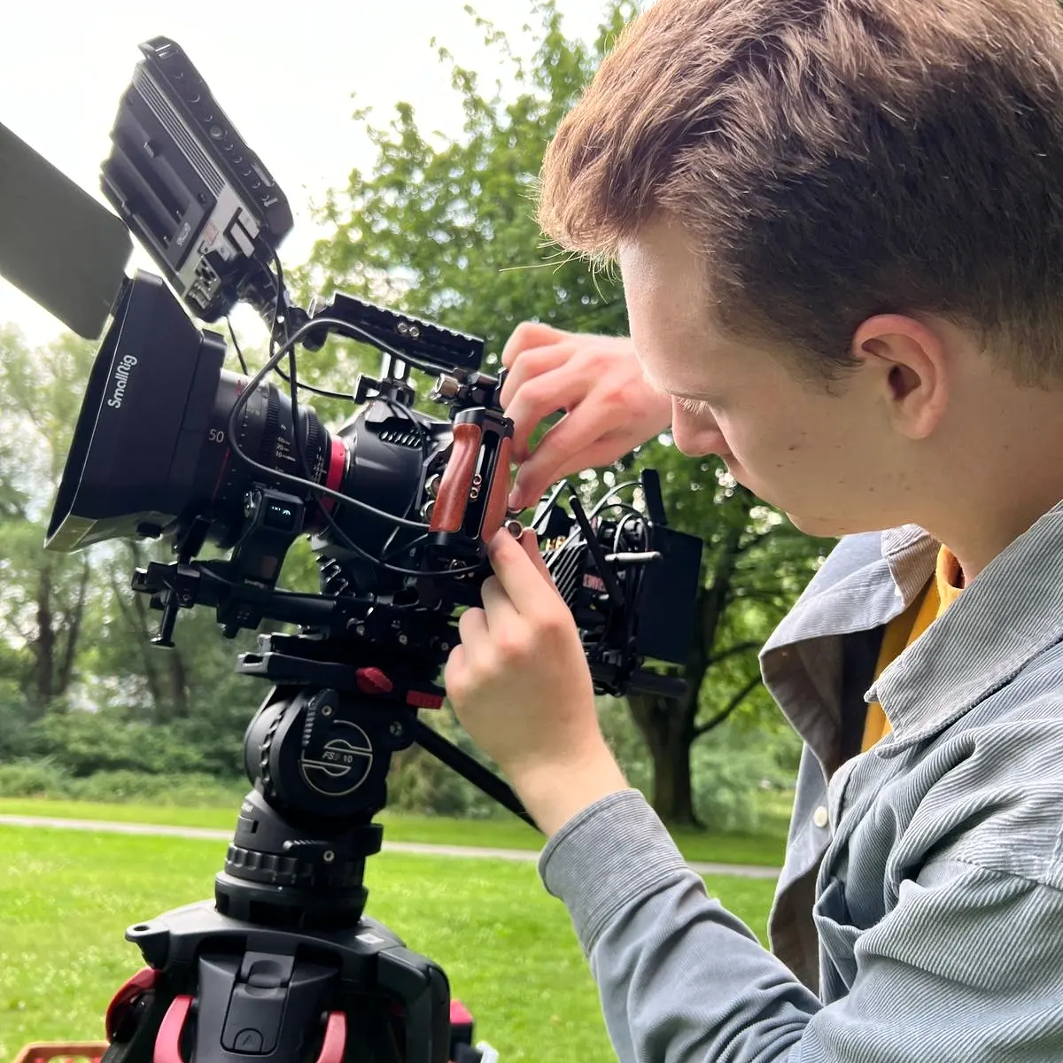 Kameraaufbau bei einem Filmdreh in der Natur, umgeben von Bäumen und Wiese, das Team bereitet die Szene vor.