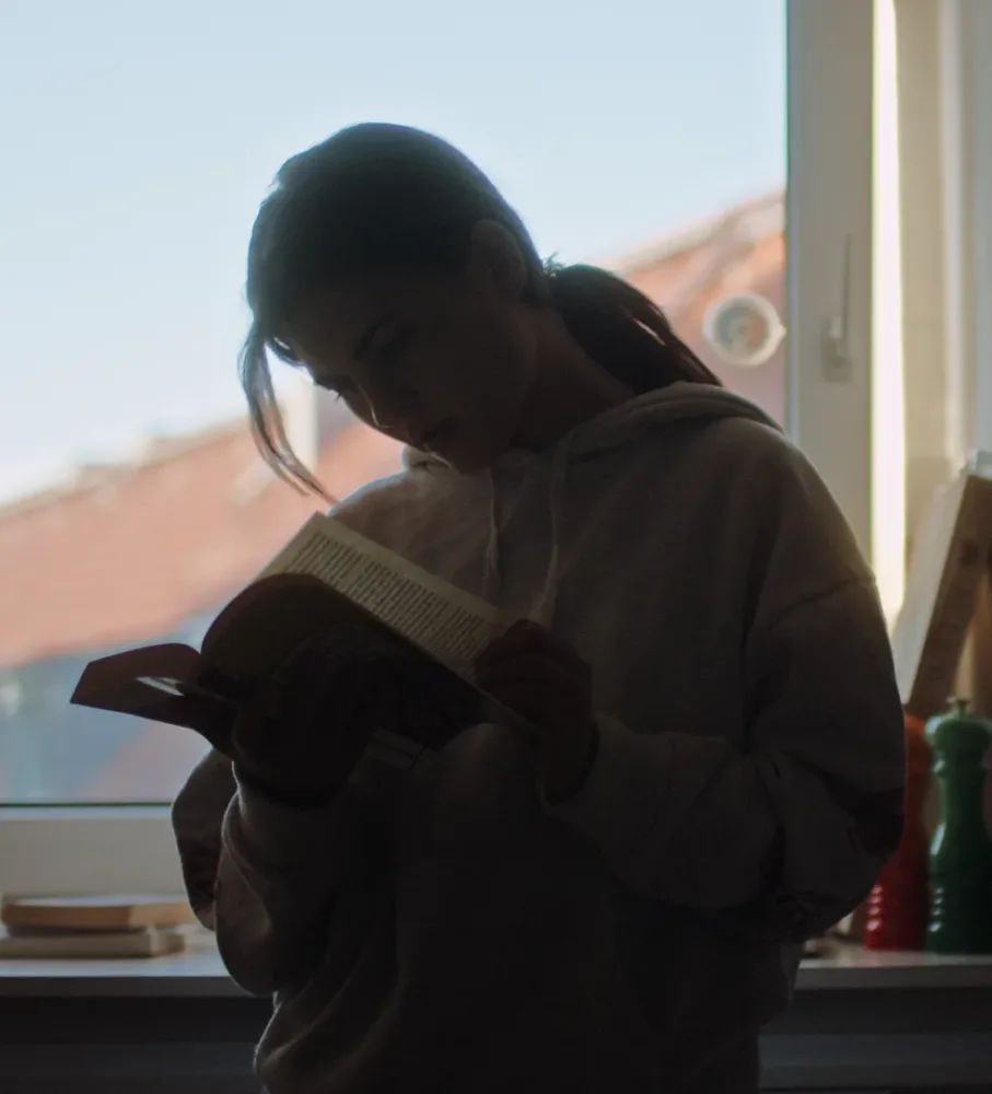 Charlotte Durbass bei den Dreharbeiten von "You’re Gonna Carry That Weight" von Cem Grönzin welche ein Buch in der Küche liest